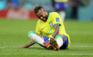Neymar caído em campo, com a mão no tornozelo direito, durante partida de estreia na Copa do Mundo do Qatar