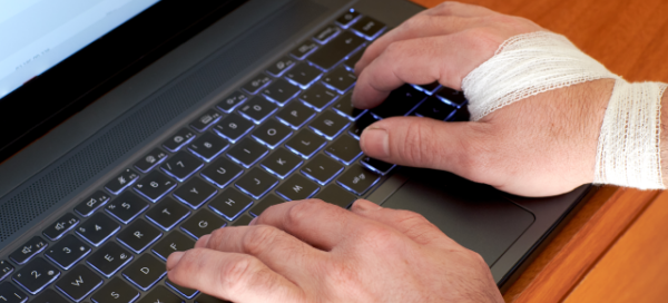 Mão masculina com atadura mexendo em um laptop