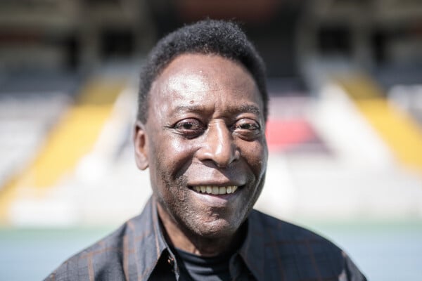 Foto aproximada de Pelé sorrindo para a câmera, vestindo camisa xadrez escura