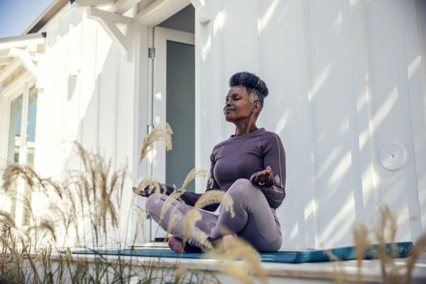 Mulher idosa negra meditando na varanda de sua casa