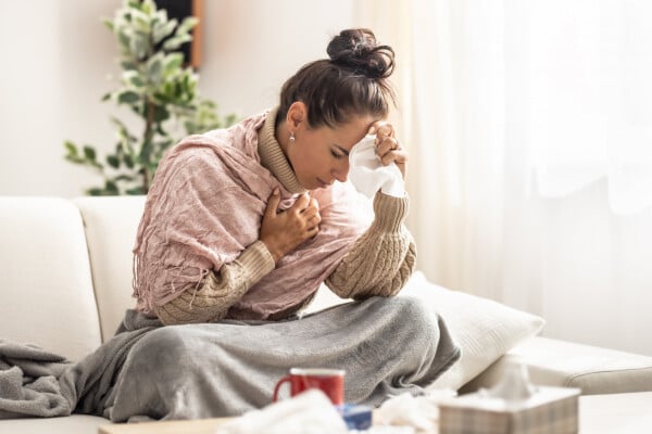 Mulher com sintomas de gripe em casa