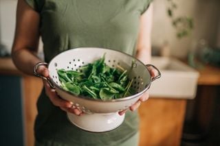 Mulher segurando uma caçarola com folhas verdes