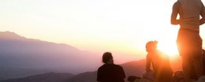 Três pessoas observando o por do sol em uma montanha