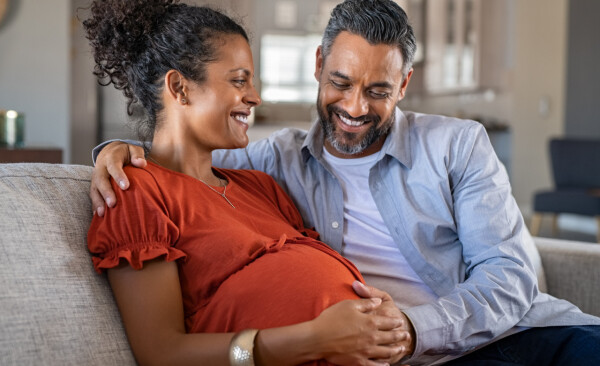 Jovem casal esperando um bebê enquanto o homem coloca a mão sobre a barriga da mulher grávida