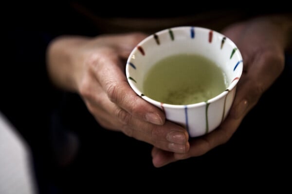 Mão feminina segurando uma xícara de chá verde