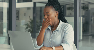 Mulher bocejando em frente ao notebook enquanto trabalho