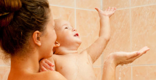 Mãe segurando filho no colo embaixo do chuveiro
