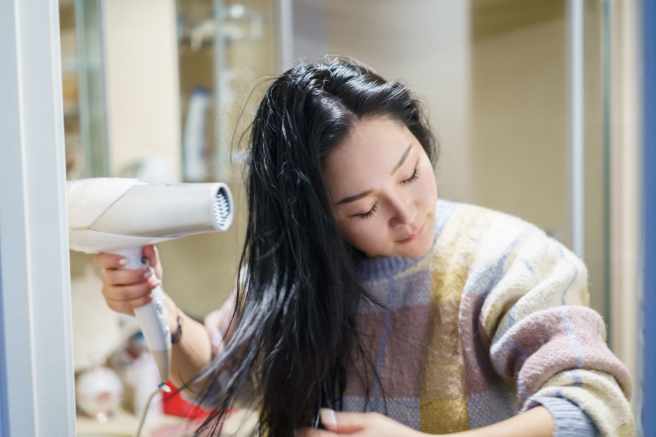 Mulher secando o cabelo com secador branco