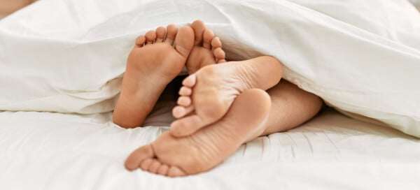 Imagem dos pés de um casal na cama