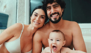 Thaila Ayala  e Renato Goés sorrindo enquanto seguram o filho Francisco, de 11 meses de idade