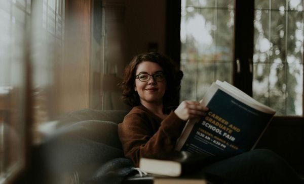 Mulher lendo jornal sentada no sofá