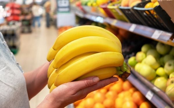 mulher segurando um cacho de bananas no mercado