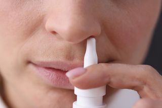 Pessoa utilizando descongestionante nasal em spray