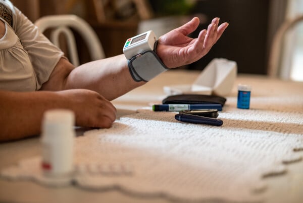 Retrato de mulher medindo a pressão arterial em casa com a ajuda de um aparelho