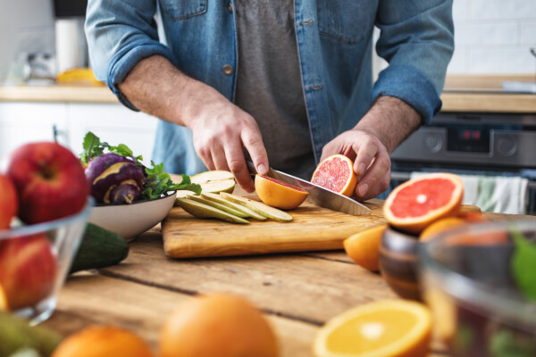 Homem segurando uma faca cortando fruta