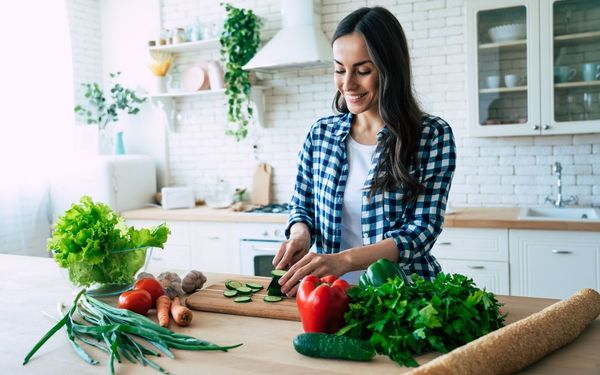 Mulher cortando vegetais em sua cozinha