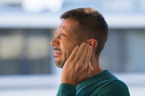 Homem tocando sua orelha por causa de dor forte no ouvido ou dor no ouvido