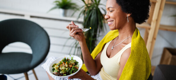 Mulher negra come um prato de salada variada