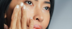 Mulher aplicando creme na área dos olhos
