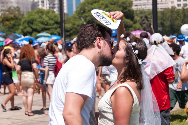 Homem e mulher dando beijo na boca em meio a carnaval de rua