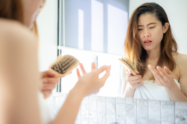 Mulher observando a escova com muitos fios de cabelo