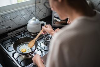 Mulher fritando um ovo em frigideira