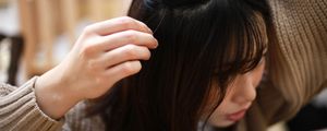 mulher asiática tocando uma mecha do cabelo em que há um cabelo branco