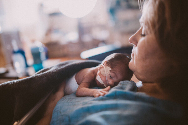 Bebê recém-nascido prematuro deitado no peito de sua mãe, em uma cama de hospital