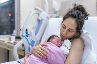 Mãe segurando o filho recém nascido no colo após o parto