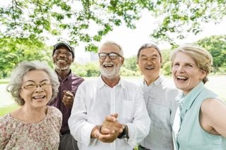 Cinco idosos sorrindo em um parque