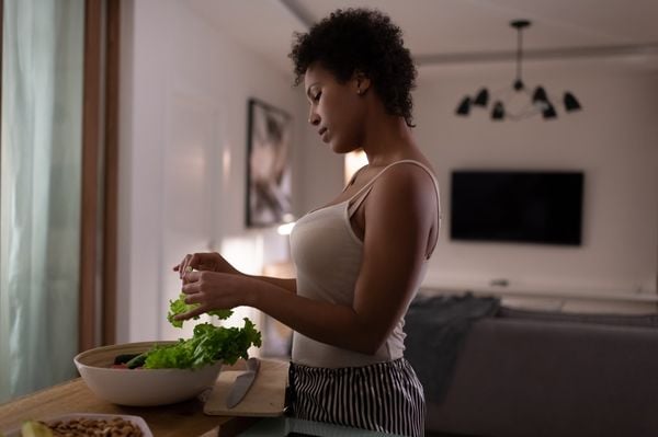 Mulher jovem na cozinha, manipulando folhas de alface