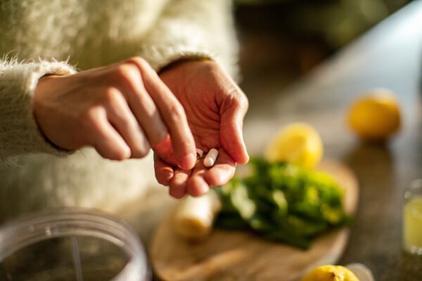 Recorte de imagem das mãos de uma mulher com cápsulas de suplementos alimentares