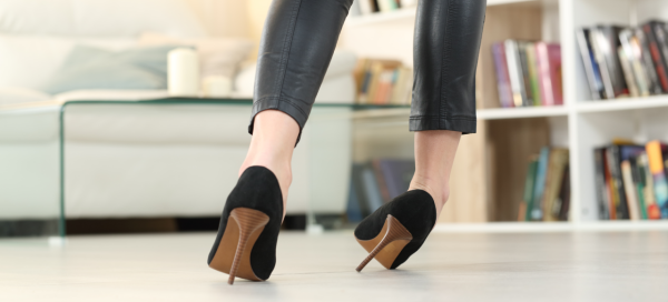 Mulher de sapato de salto alto preto se desequilibra e torce o tornozelo