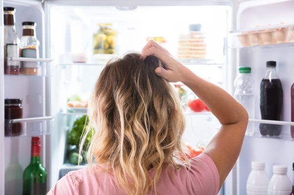 Mulher confusa em frente geladeira