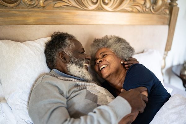 Casal maduro sorrindo enquanto estão deitados em cama