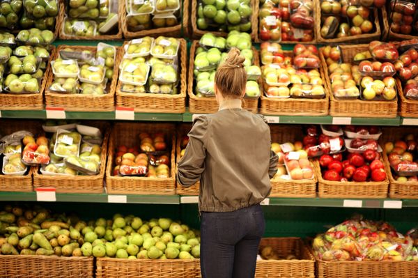 Mulher de costas escolhendo frutas no mercado