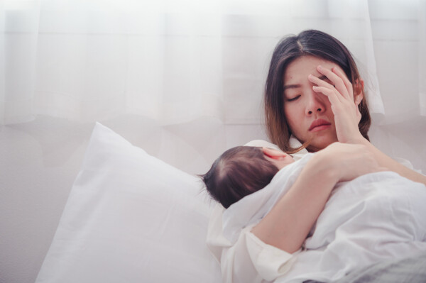 Mãe cansada e triste, com depressão pós-parto, segurando seu bebê