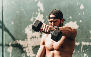 Imagem aproximada de homem fazendo exercício com halteres