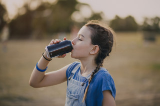 Criança bebendo um refrigerante de olhos fechados