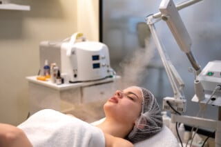 Paciente, mulher branca, recebendo ozonioterapia por vapor no rosto, durante tratamento estético