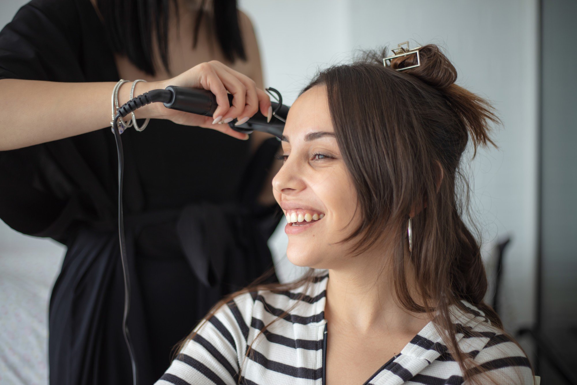 Mulher passando chapinha no cabelo de cliente