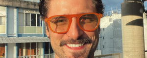 ator daniel rocha sorrindo usando um óculos redondo laranja