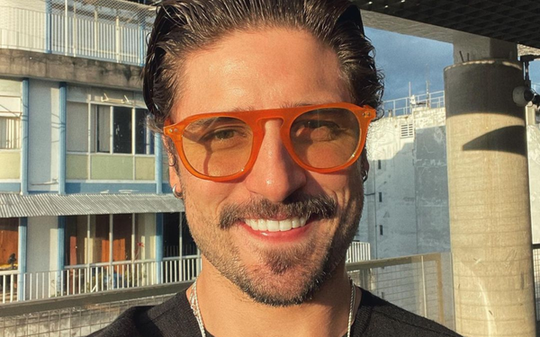 ator daniel rocha sorrindo usando um óculos redondo laranja