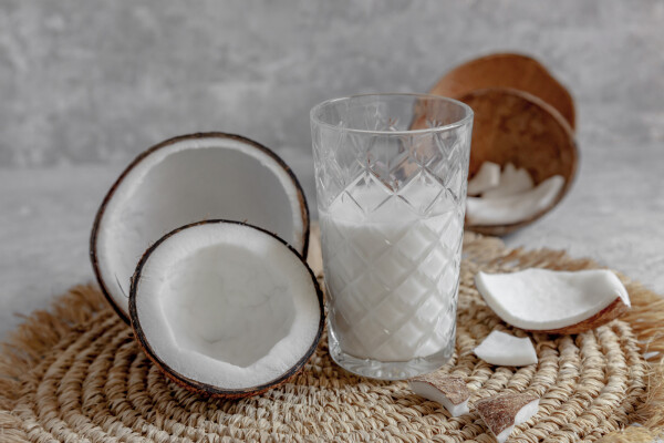 copo de leite de coco e coco aberto em uma mesa