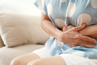 Mulher com dor de barriga por conta de doença de Crohn