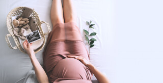 Mulher grávida com imagem de ultra-som. Mãe com cesta de vime de pequenas coisas fofas e brinquedo de ursinho de pelúcia para recém-nascido.
