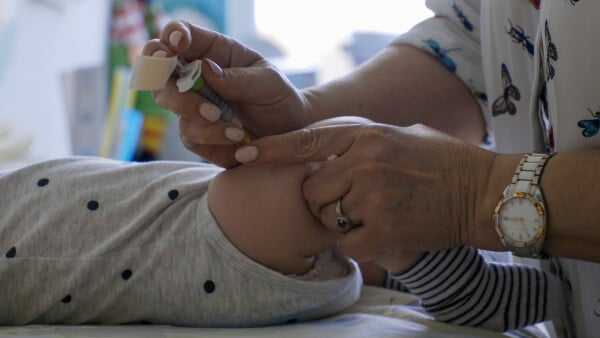 Bebê recebendo injeção na perna em consultório pediátrico