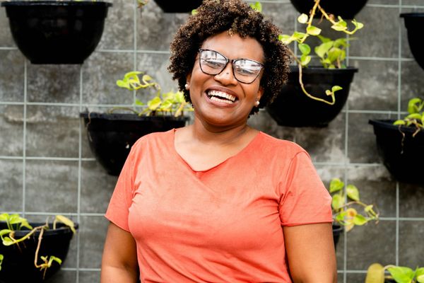 Mulher feliz e muito sorridente em frente a um jardim vertical