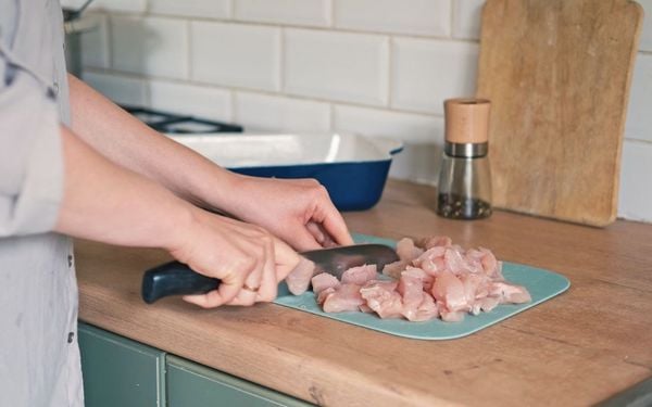 pessoa cortando frango em uma tábua