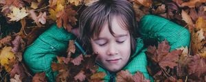 foto de menino deitado entre as folhas secas